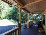 The covered front porch looks out toward a fire pit and picnic table